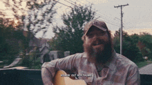 a man with a beard is singing while holding a guitar with the words holdin ' out her thumb above him