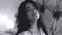 a black and white photo of a woman with long hair looking at the camera