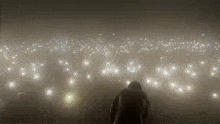 a man in a hooded jacket stands in front of a crowd of lights