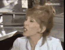 a woman with red hair is sticking out her tongue while sitting at a table .