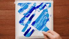 a person is painting a blue and white picture with a brush