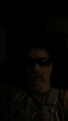 a man with a beard wearing sunglasses in a dark room