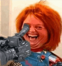 a chucky doll is laughing while holding a camera .