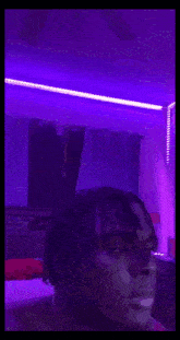 a man is smoking a hookah in a purple room with purple lights .
