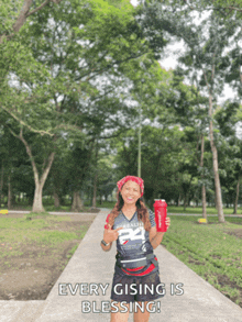 a woman holding a red bottle with the words every gising is blessing
