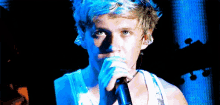 a man is singing into a microphone with a blue background