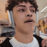 a man with curly hair wearing headphones and a white shirt