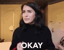 a woman in a black sweater says " okay "
