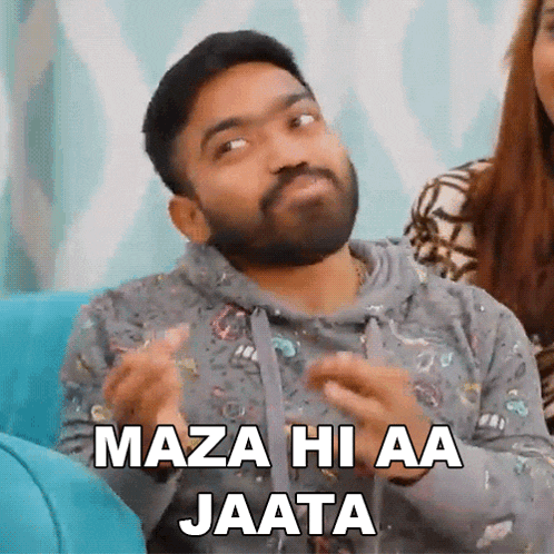 a man with a beard is sitting on a blue couch with the words maza hi aa jaata above him