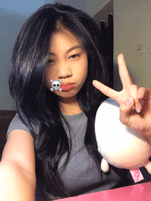 a girl with a skull and crossbones on her face giving a peace sign