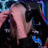 a woman wearing headphones is covering her face with her hands