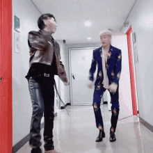 two men are dancing in a hallway in front of a red door .