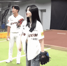 a man and a woman are standing on a baseball field and the woman is wearing a jersey that says kingdom
