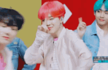 a man with pink hair is making a heart with his finger