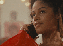 a woman is talking on a cell phone with a red bag behind her