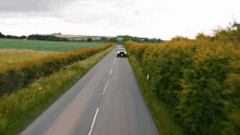 a car is driving down a country road surrounded by trees