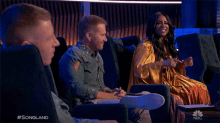 a man and a woman are sitting on a couch and the man is pointing at something