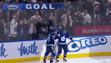 toronto maple hockey players celebrate a goal in front of a crowd