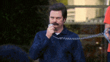 a man with a mustache talking on a telephone