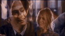 a man and a woman are smiling and looking at each other in a blurry photo .