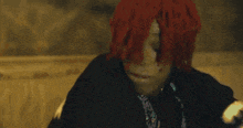 a man with red hair and dreadlocks is sitting on a bed