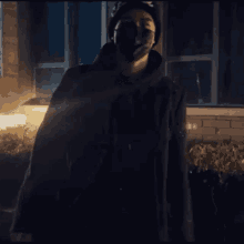 a man wearing a black mask and a black jacket stands in front of a building