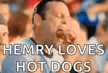 a man is eating a hot dog with the caption " henry loves hot dogs "
