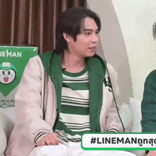 a man wearing a green jacket is sitting in front of a lineman sign