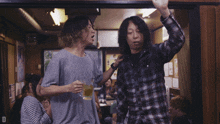 a man in a plaid shirt is talking to another man