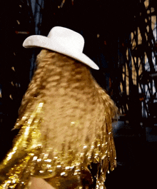 a woman wearing a white cowboy hat and gold fringe