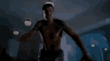a shirtless man is standing in a dark room .