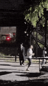 a man in a suit and a woman in a white shirt are running down a street at night .
