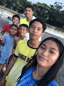 a boy wearing a yellow shirt that says " just 2 a " poses with his friends