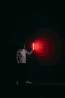 a man in a suit holds a red light in front of a brick wall