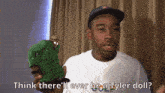 a man in a white shirt is holding a green figurine and asking if he 'll ever be a tyler doll