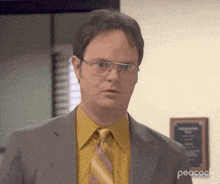 dwight schrute from the office is wearing glasses and a yellow shirt and tie .