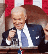 a man in a suit and tie is smiling while holding a glass