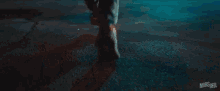 a man in a hoodie is standing in the dark in front of a fence .