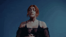 a woman with red hair and a tattoo on her arm is singing with her eyes closed