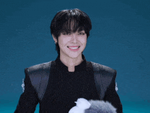 a young man wearing a black jacket and furry gloves smiles
