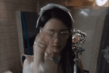 a woman wearing glasses is looking at herself in the mirror