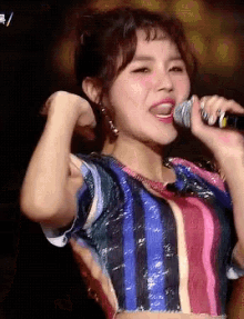 a woman is singing into a microphone and flexing her muscles .