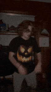 a man in a black shirt with a pumpkin on it is dancing in a dark room