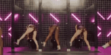 a group of women are standing on their knees in front of a pink wall .