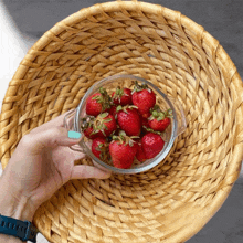 a person holding a glass bowl of strawberries