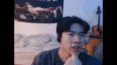 a man is making a funny face in front of a guitar and a poster of a man laying on a bed .