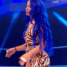 a woman with blue hair is standing in a wrestling ring with the words live on the bottom