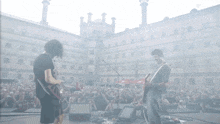 two men playing guitars in front of a crowd of people