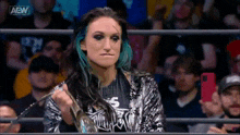 a woman with blue hair is standing in a wrestling ring holding a trophy .