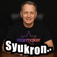 a man wearing a shirt that says syukron sits in a chair